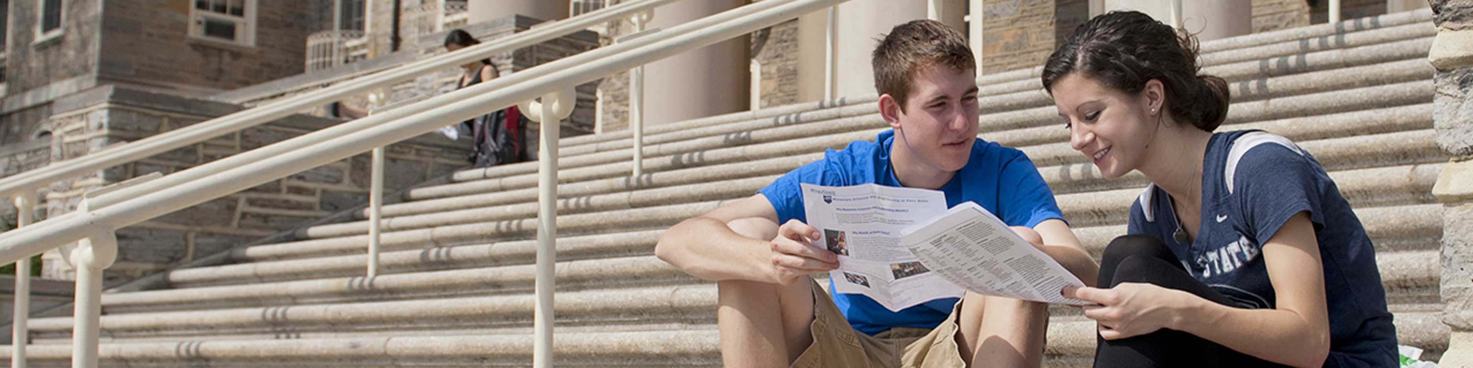 students on sitting on steps of old main